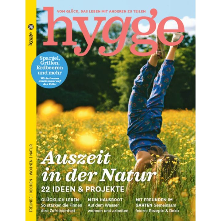 Titelbild der Zeitschrift „hygge“ mit einem Kind in blauer Kleidung, das auf einer Wiese einen Handstand macht; Überschrift: „Auszeit in der Natur – 22 Ideen & Projekte“, daneben Themen wie Spargel, Grillen und Erdbeeren.