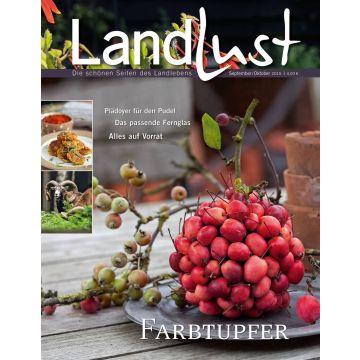 Magazincover "Landlust" September/Oktober 2015 zeigt eine dekorative Anordnung von roten Beeren und Zweigen auf einem Tisch. Links oben sind kleine Bilder, darunter ein Gericht und ein Widder. Themen: Pudel, Fernglas, Vorrat.