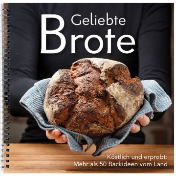 Eine Person hält ein rundes, gebackenes Brot in einem Handtuch. Auf dem Cover steht "Geliebte Brote", darunter "Köstlich und erprobt: Mehr als 50 Backideen vom Land". Spiralbindung erkennbar.