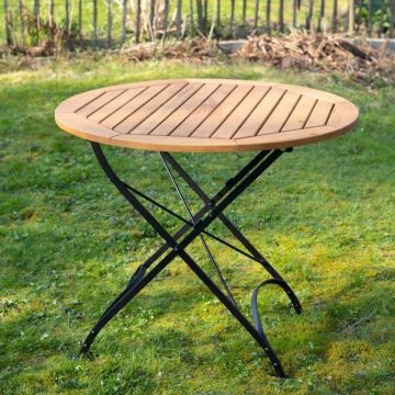 Runder Gartentisch mit hölzerner Tischplatte und schwarzen Metallbeinen, stehend auf einer grünen Rasenfläche.