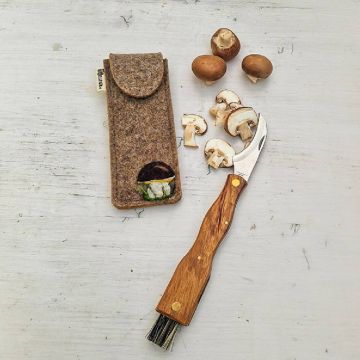 Pilzmesser mit Holzgriff und Reinigungsbürste, daneben geöffnete Filztasche; aufgeschnittene braune Champignons auf weißem Hintergrund.