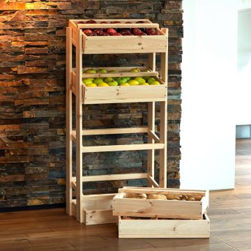 Ein Holzregal mit vier Ebenen, gefüllt mit roten und grünen Äpfeln. Vor dem Regal stehen zwei leere Holzkisten auf einem Holzfußboden, die Steinwand im Hintergrund ist dunkel gefliest.