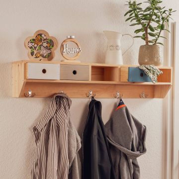 Ein hölzernes Wandregal mit Kleiderhaken darunter. Auf dem Regal stehen Dekorationsgegenstände, darunter ein Keramikkrug, eine Vase mit Pflanze und ein Schild mit "Home". An den Haken hängen Jacken und ein gestreiftes Hemd.