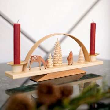 Holzdeko mit zwei roten Kerzen, leicht gebogenem Rahmen und Figuren: Rehe und Bäume. Auf stabiler Basis, minimalistisch und elegant gestaltet, auf einer glatten Oberfläche präsentiert.