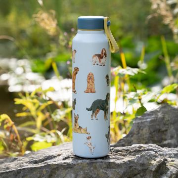 Hohe, hellblaue Trinkflasche mit hellgrauem Deckel und gelbem Trageband, im Freien auf einem Felsen stehend; der Flaschenkorpus ist ringsum mit farbigen Illustrationen verschiedener Hunderassen in unterschiedlichen Posen bedruckt.