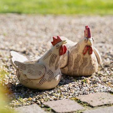 Zwei cremefarbene Hühnerfiguren aus Keramik mit roten Kämmen, feinen Linienmustern und rauer, strukturierter Oberfläche.