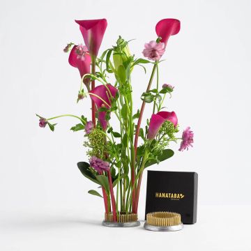 Ring zum Blumenstecken aus Metall mit goldenen Spitzen, verschiedene pinke Blumen und grüne Stiele darin arrangiert.