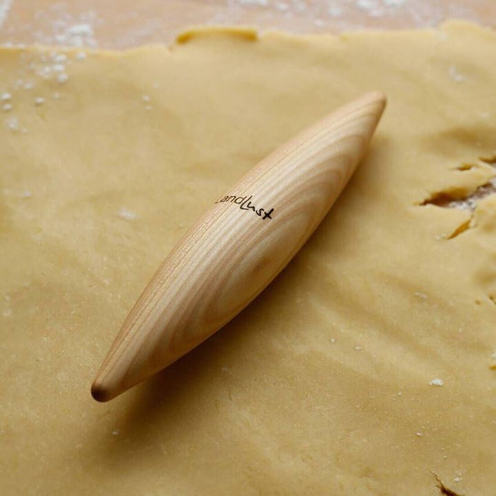 Ein konisch geformter Holz-Teigroller liegt auf ausgerolltem Teig; auf dem Roller ist das Logo &bdquo;Landlust&ldquo; sichtbar.