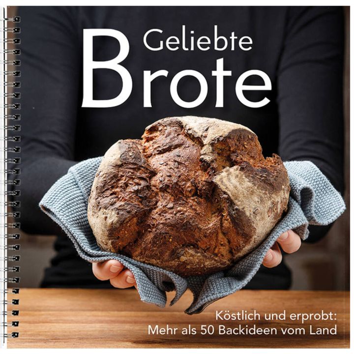 Eine Person h&auml;lt ein rundes, gebackenes Brot in einem Handtuch. Auf dem Cover steht "Geliebte Brote", darunter "K&ouml;stlich und erprobt: Mehr als 50 Backideen vom Land". Spiralbindung erkennbar.