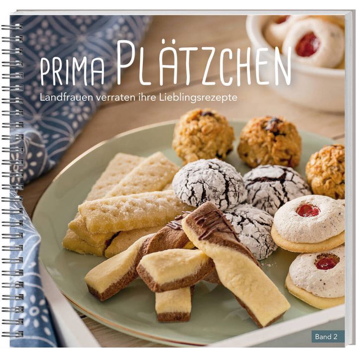Ein spiralgebundenes Backbuch mit dem Titel &bdquo;Prima Pl&auml;tzchen &ndash; Landfrauen verraten ihre Lieblingsrezepte, Band 2&ldquo;. Auf dem Cover sind verschiedene Pl&auml;tzchen auf einem Teller arrangiert, darunter Schokocookies, Kokosmakronen und Buttergeb&auml;ck.