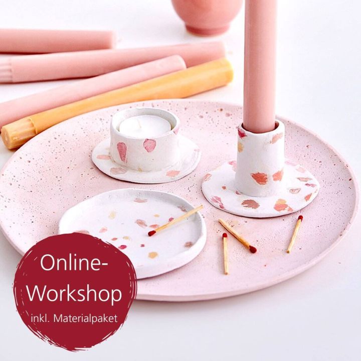 Ein rosa Tablett mit Kerzenhaltern, Teelicht und Streichhölzern, verziert mit bunten Tupfen. Vordergrund: Schriftzug "Online-Workshop inkl. Materialpaket". Meist helle, pastellfarbene Objekte.