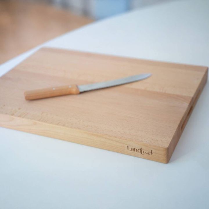 Gro&szlig;es, rechteckiges Holzschneidebrett mit der Gravur &bdquo;Landlust&ldquo; an der unteren rechten Ecke, auf einem wei&szlig;en Hintergrund. Die Maserung des Holzes ist gleichm&auml;&szlig;ig und deutlich sichtbar.