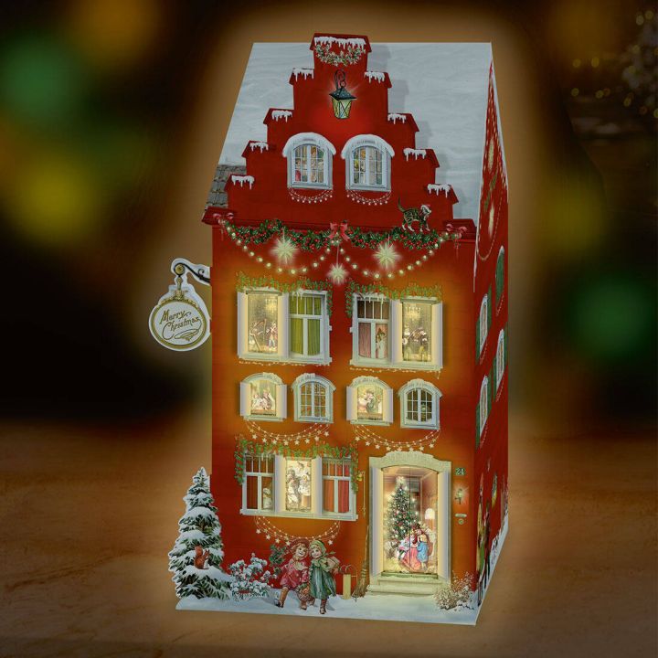 Illustrierter Adventskalender in Form eines festlich dekorierten, rot gestrichenen Hauses mit Fenstern, durch die weihnachtliche Szenen leuchten, und einer verschneiten Tanne im Vordergrund, aufgestellt vor einem unscharfen Hintergrund.