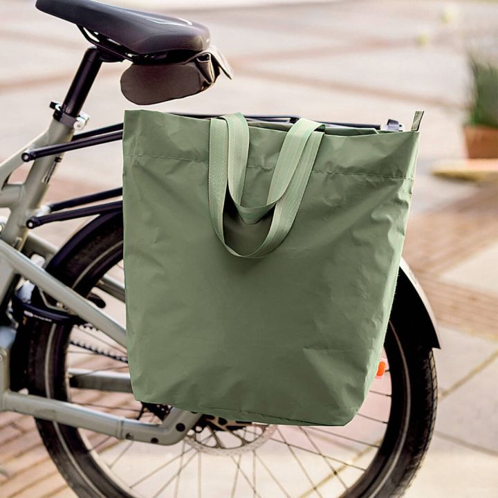 Gro&szlig;e, gr&uuml;ne Fahrradtasche in Shopper-Form mit zwei Tragehenkeln, seitlich am Gep&auml;cktr&auml;ger eines Fahrrads befestigt; Fokus auf Gr&ouml;&szlig;e und einfache Befestigung der Tasche am Rad.