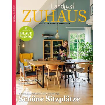Titelbild der Zeitschrift „Landlust Zuhause“ mit einer Frau in einem Esszimmer, Holztisch mit Stühlen, Blumenstrauß, gelber Sessel, blau gestrichene Wand, grüner Pflanzenakzent; Textinhalte zu Wohnen, Renovieren und Dekorieren.