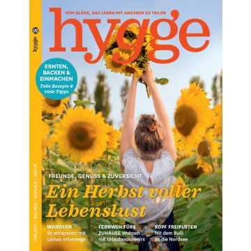Titelblatt der Zeitschrift "hygge" mit Haupttitel "Ein Herbst voller Lebenslust". Eine Person im Sommerkleid hält einen Strauß Sonnenblumen, umgeben von Sonnenblumenfeld, in die Höhe. Oben links Themen: Ernten, Backen & Einmachen.