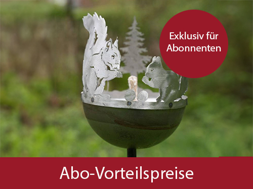 Eine Gartenfackel aus Metall ist mit einer Grafik von Eichh&ouml;rnchen verziert. Sie steht vor einem gr&uuml;nen Garten-Hintergrund.