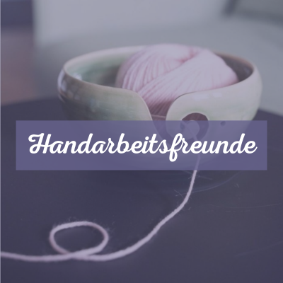 Eine grüne Garnschale aus Keramik mit lila-farbener Wolle steht auf einem kleinen Tisch. Text: Handarbeitsfreunde