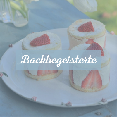 Auf einem weißen Teller mit Rosen am Rand sind drei Erdbeer-Törtchen. Text: Backbegeisterte