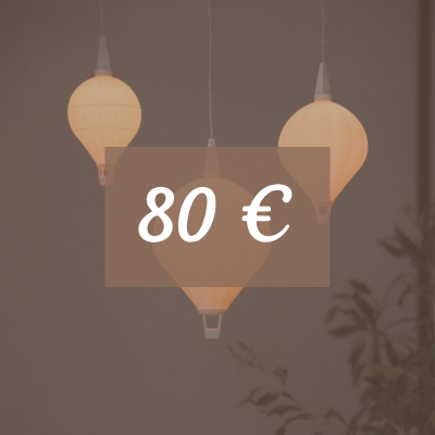 Drei leuchtende Heißluftballon-Lampen hängen herunter. Daneben steht eine Pflanze. Text: 80 Euro