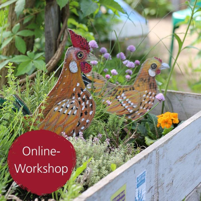Gebastelte Hühner aus Pappe stehen in einem blühenden Beet