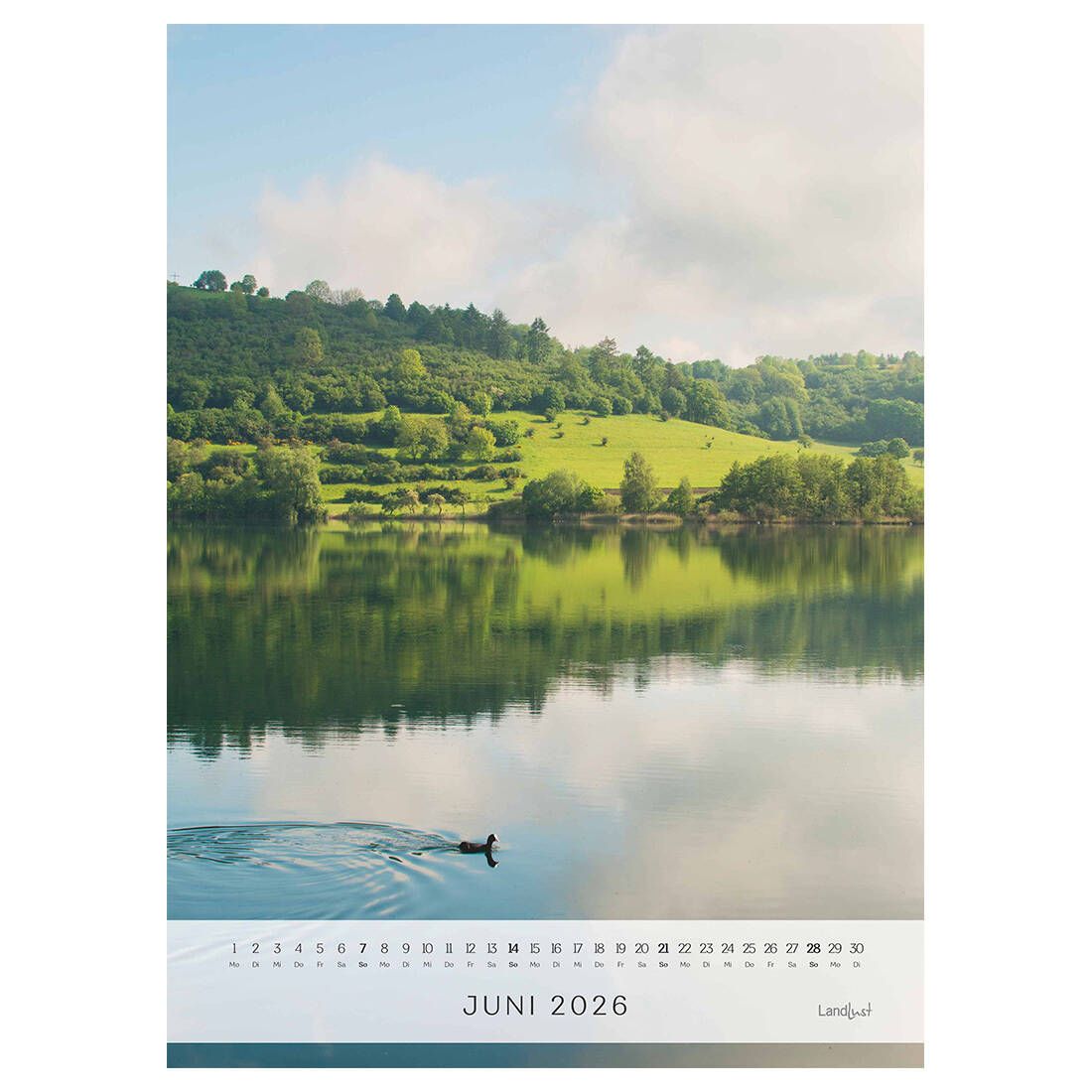 Das Kalenderblatt im Juni zeigt einen ruhigen See indem sich die grüne Hügellandschaft und der blaue Himmel mit weißen Wolken spiegelt.