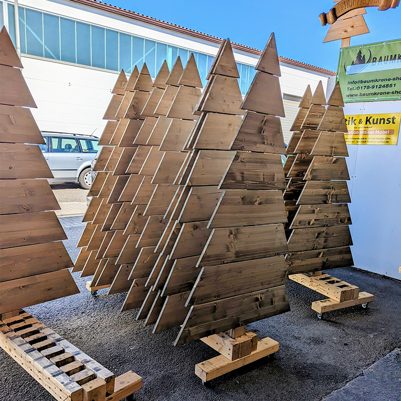 Viele große Holzprodukte in Tannenbaumform stehen im Außenbereich in einer Reihe