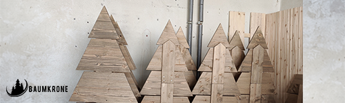 Vor einer grauen Betonwand stehen Bäume aus Holz