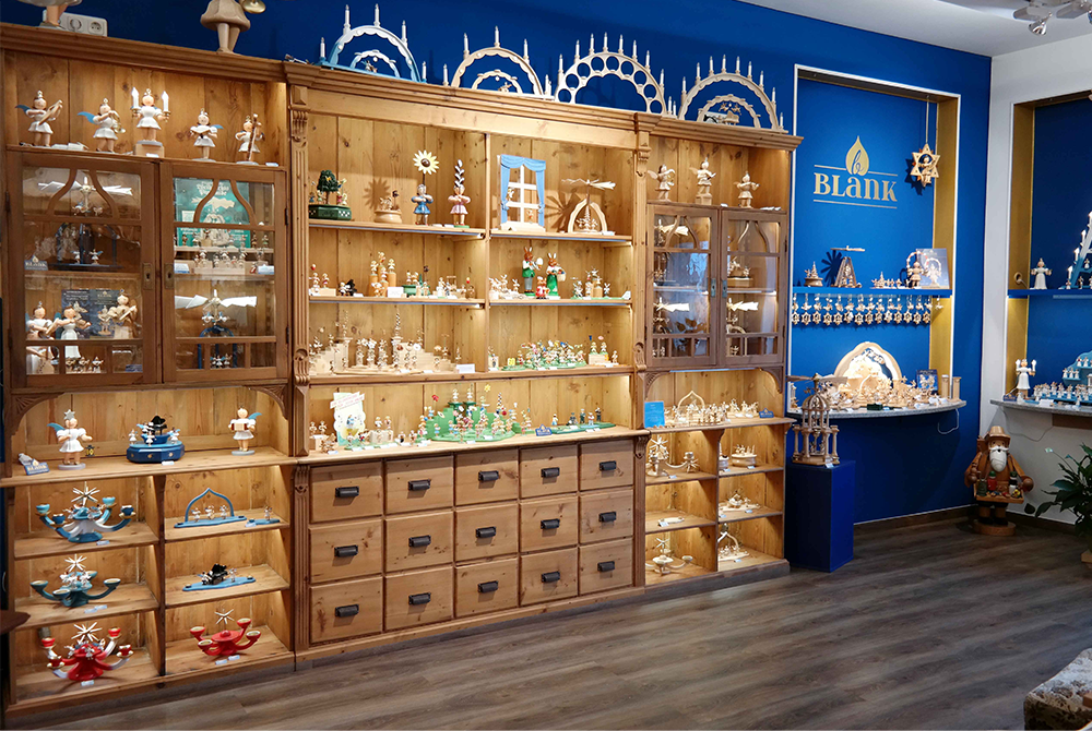 Das Geschäft von BLANK Kunsthandwerk. Im Regal stehen viele unterschiedliche Holzfiguren