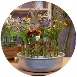 Blumen stehen aufrecht innerhalb eines Blechtopfs auf einem Tisch.