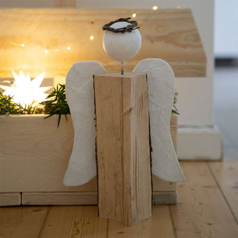 Ein Engel bestehend aus einem Holzfeuerscheit, Styroporkugel und Gipsflügeln steht auf einem Hoolzboden