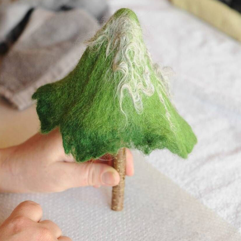 Ein Tannenbäumchen wird gefilzt. Getrocknet und mit Stamm aus einem Ast, ist das Tannenbäumchen fertig