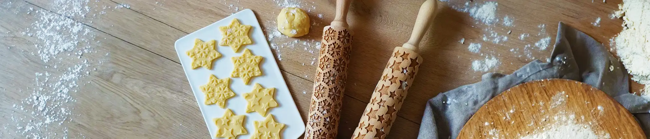 Zwei Teigrollen mit denen die Motive Stern oder Schneeflocke auf Plätzchen gedruckt werden können liegen auf einer bemehlten Arbeitsplatte.