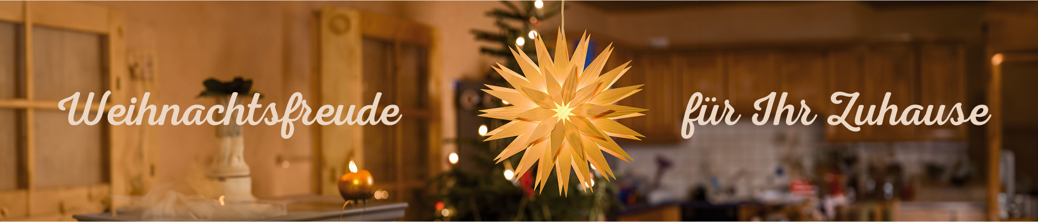 Ein leuchtender, goldener Stern hängt vor einem verschwommenen Hintergrund, der eine festlich dekorierte Küche mit warmen Lichtern und Holzelementen zeigt. Links steht der Text "Weihnachtsfreude" und rechts "für Ihr Zuhause" in geschwungener Schrift.