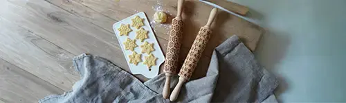 Zwei Teigrollen mit denen die Motive Stern oder Schneeflocke auf Plätzchen gedruckt werden können liegen auf einer bemehlten Arbeitsplatte.