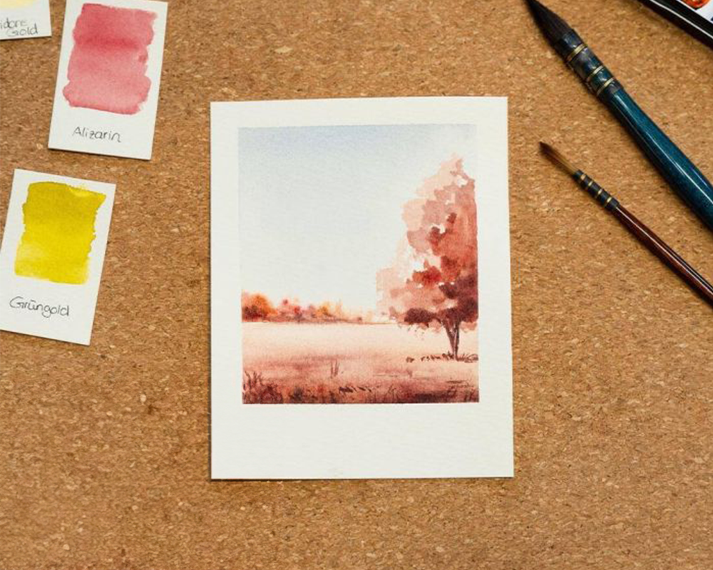 Eine rötlich, gemalte Herbstlandschaft auf Aquarellpapier, daneben ein Pinsel und Farbkarten, Bild verlinkt zum Workshop.
