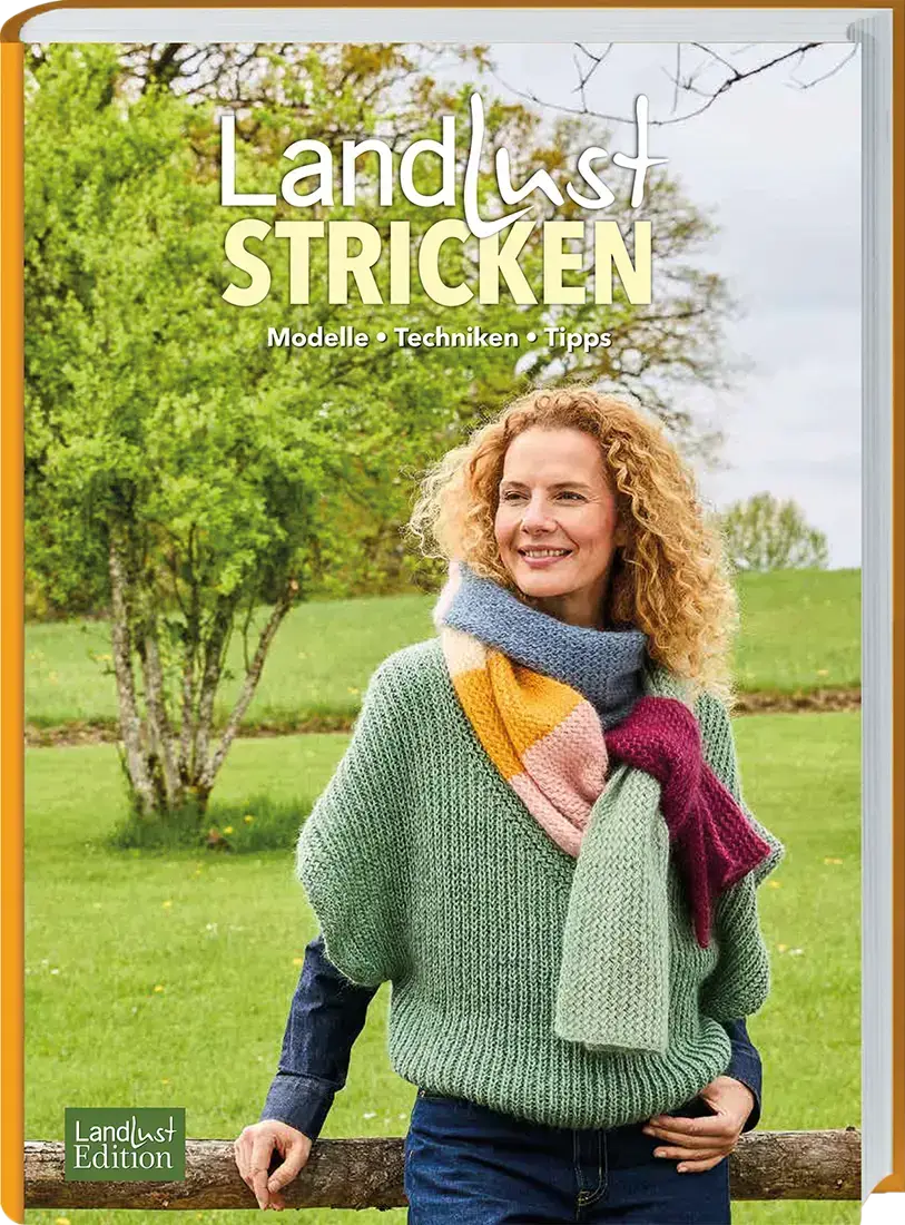 Ein Buch von Landlust &uuml;ber das Thema Stricken. Man sieht eine Frau im freien, welche sich an einen Holzzaun lehnt. Sie tr&auml;gt einen t&uuml;rkisen Strickpullover und einen Strickschal aus mehreren Farben. 