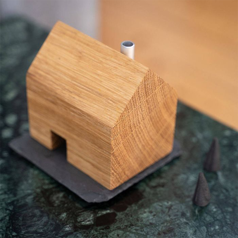 Ein Räucherhäuschen aus Holz steht auf einer Steinplatte