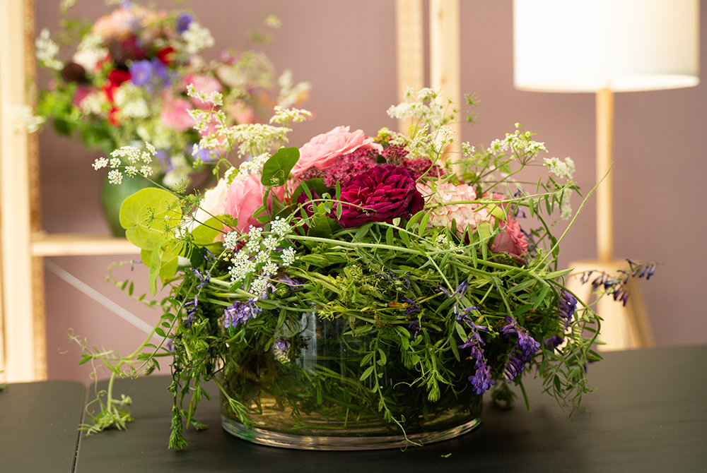 Ein rundes Gesteck mit grünen Zweigen und roten sowie rosa Rosen