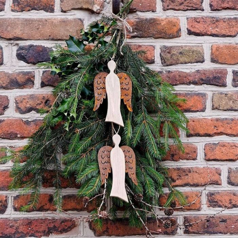 Zwei Engel aus Holz mit rostfarbenen Flügeln hängen an einem Ast.