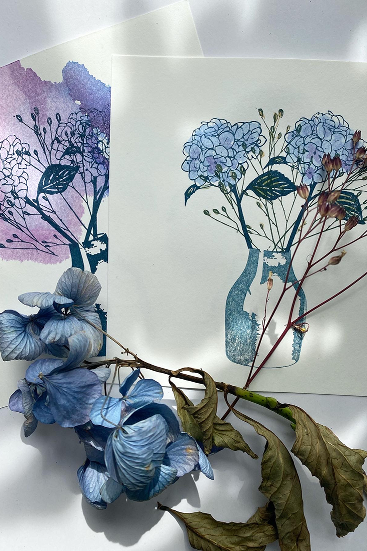 Grauer Tonw&uuml;rfel mit eingraviertem Herzmuster, glatte Oberfl&auml;che, daneben liegen d&uuml;nne Holzst&auml;bchen auf hellem Untergrund.