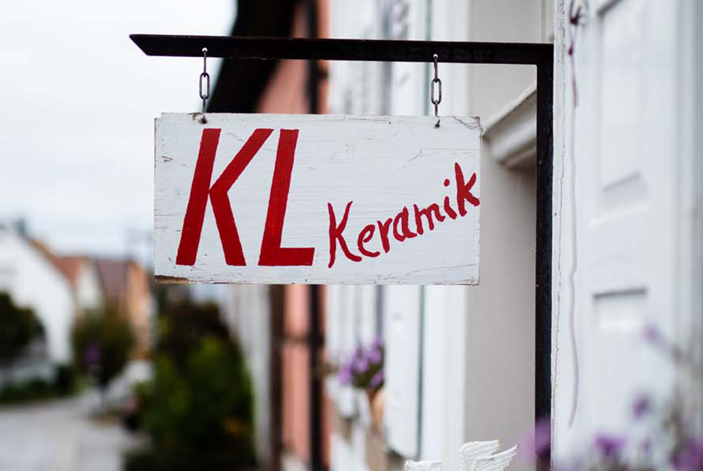 Ein Schilder mit der Aufschrift "KL Keramik" hängt draußen vor einem Haus