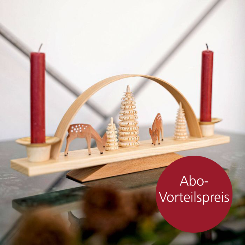 Ein Schwibbogen aus Holz mit zwei roten Kerzen und zwei Reh-Figuren steht auf einem Tisch