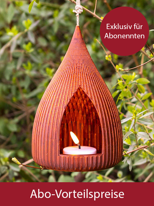 Amberfarbene, tropfenförmige Laterne mit Rillen und offener Vorderseite, LED-Licht innen, grüner Hintergrund mit Blättern.