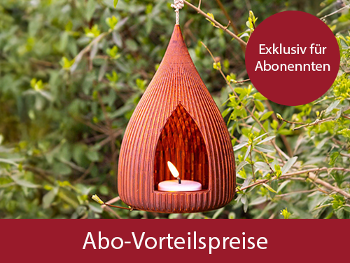 Amberfarbene, tropfenförmige Laterne mit Rillen und offener Vorderseite, LED-Licht innen, grüner Hintergrund mit Blättern.
