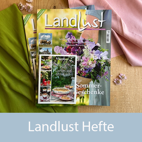 Zwei „Landlust“-Magazine liegen auf einem hellen Untergrund, umgeben von unterschiedlichen Stoffen und kleinen rosa Blüten. Bild verlinkt zu dem neuen Landlust Heft.