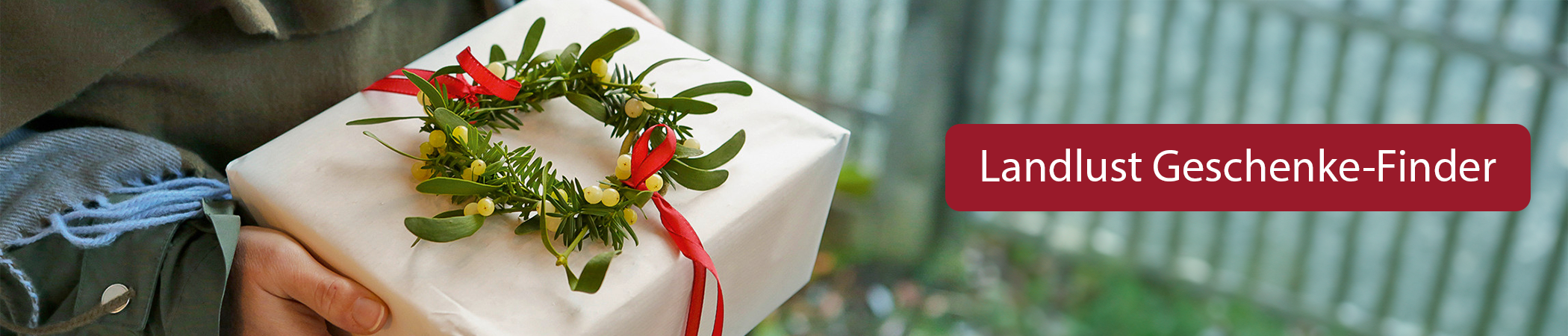 Eine Person hält ein Geschenk in der Hand. Text: Landlust Geschenke-Finder