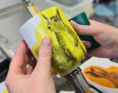 Eine Tasse mit Eichhörnchen-Motiv ist gelb überlackiert