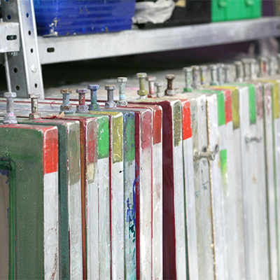 Bunte Siebdruckrahmen stehen nebeneinander im Regal