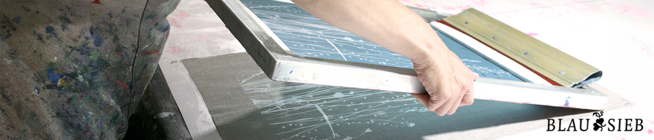 Eine Person macht Siebdruck. Sie ist dabei ein belichtetes Sieb auf eine Unterlage zu legen